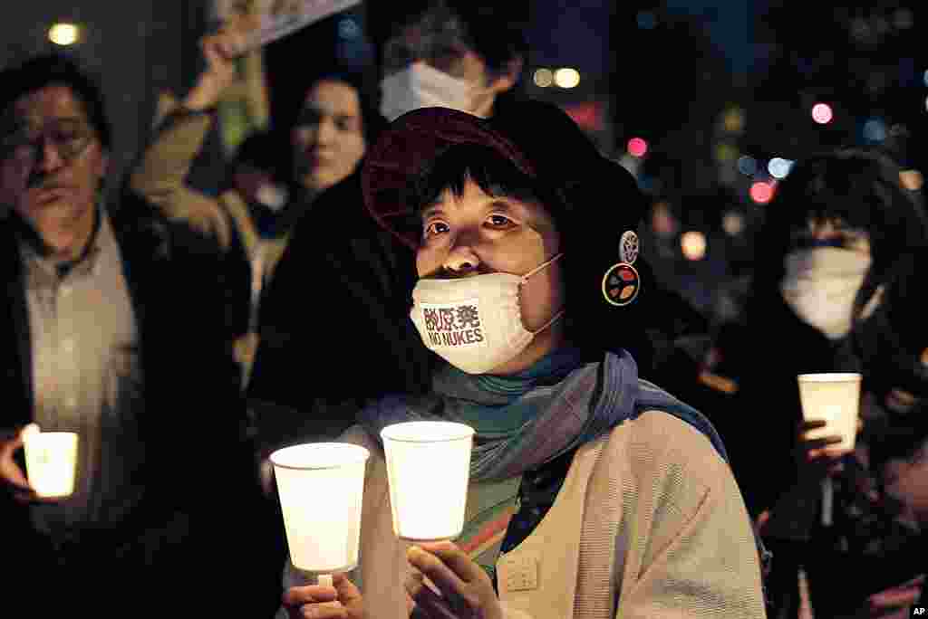 A woman wearing a "No Nukes" mask attends a candle light vigil marking the 25th anniversary of Chernobyl nuclear disaster in Ukraine during an anti-nuclear protest in Tokyo in front of the headquarters of Tokyo Electric Power Company, April 26, 2011. (AP)
