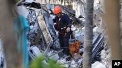 Fire rescue personnel conduct a search and rescue with dogs through the rubble of the Champlain Towers South Condo after the multistory building partially collapsed in Surfside, Fla., June 24, 2021. 
