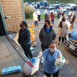 People “social distance” while they wait their turn to pick up the fixings for a Thanksgiving meal, at Food for Others in Fairfax, Virginia. (Deborah Block/VOA)