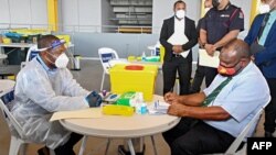 Esta foto tomada el 30 de marzo de 2021 muestra al primer ministro de Papúa Nueva Guinea, James Marape, preparándose para recibir una dosis de la vacuna AstraZeneca COVID-19, en Port Moresby, Papúa Nueva Guinea.