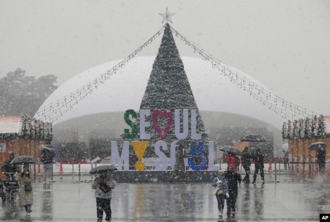 FILE - People pass by a Christmas tree in the snow at Gwanghwamun Square in Seoul, South Korea, Tuesday, Jan. 9, 2024. (AP Photo/Ahn Young-joon)