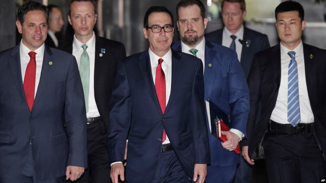 Menteri Keuangan AS Steven Mnuchin (tengah) dikawal oleh para pengawalnya dan delegasi meninggalkan hotel di Beijing, 29 Maret 2019.
