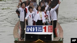 Yingluck Shinawatra, center, opposition Pheu Thai Party's candidate for prime minister and youngest sister of ousted PM Thaksin Shinawatra, gestures from a boat during her election campaign rally at a canal on the outskirts of Bangkok, Thailand, June 30, 