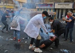 Iraqi volunteers help a protester who was struck by a tear gas canister fired by security forces at Baghdad's Khallani square during ongoing anti-government demonstrations.