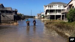 A couple walk along a road flooded with sea water brought by Hurricane Maria in Buxton, N. C., Sept. 27, 2017