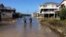 A couple walk along a road flooded with sea water brought by Hurricane Maria in Buxton, N. C., Sept. 27, 2017