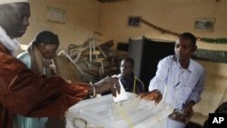 A poll worker helps a voter cast his ballot for president at a polling station in the Cambarene neighborhood of Dakar, Senegal, Sunday, Feb. 26, 2012