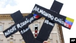 Faithful from Venezuela hold crosses with names of people who died during protests in Venezuela, during the Regina Coeli prayer led by Pope Francis in Saint Peter's Square at the Vatican, May 7, 2017. On Monday, the Vatican announced the “Bridges of Solidarity” project, an assistance program for Venezuelans fleeing their homeland.