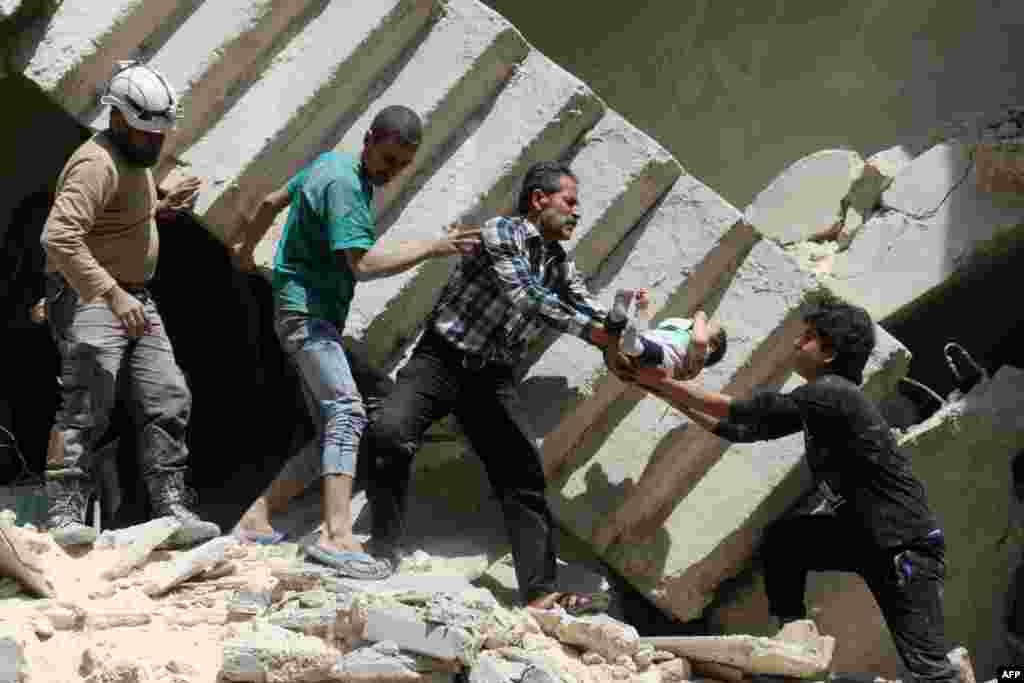 Syrian civil defense volunteers and rescuers remove a baby from under the rubble of a destroyed building following a reported air strike on the rebel-held neighborhood of al-Kalasa in the northern Syrian city of Aleppo, April 28, 2016.