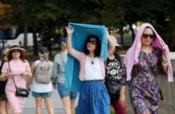 Tourists visiting the Lincoln Memorial shield themselves from the sun in Washington, Oct. 2, 2019.
