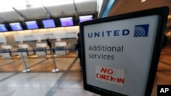 FILE - A piece of tape is affixed to a sign marking an empty line at the United Airlines ticket counter at Denver International Airport, April 16, 2016, in Denver, Colorado.