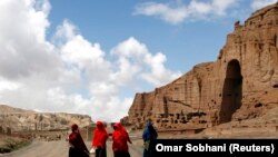 Perempuan Afghanistan berjalan di depan ceruk yang pernah terdapat patung Buddha raksasa, di Provinsi Bamiyan 21 April 2009. (Foto: REUTERS/Omar Sobhani)