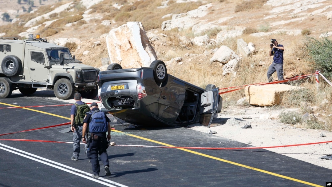 Israeli policemen walk at the scene of a shooting attack near Hebron, West Bank, July 1, 2016. A Palestinian gunman opened fire at a family traveling in a car in the West Bank on Friday, killing an Israeli man and wounding his wife and two children.