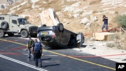 Israeli policemen walk at the scene of a shooting attack near Hebron, West Bank, July 1, 2016. A Palestinian gunman opened fire at a family traveling in a car in the West Bank on Friday, killing an Israeli man and wounding his wife and two children.