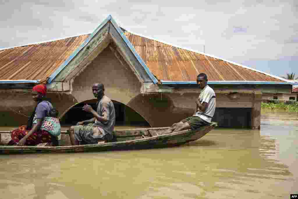 Warga duduk di perahu dayung saat mereka berpindah di antara rumah-rumah yang terendam di daerah banjir Adankolo di Lokoja, Nigeria. (AFP)&nbsp;