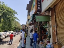 Customers head to shops selling essentials like groceries and medicines. (Anjana Pasricha/VOA)