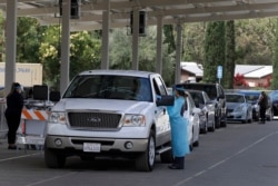 Healthcare workers take information and samples from people waiting to be tested for Covid-19, July 21, 2020, in Pleasanton, Calif.