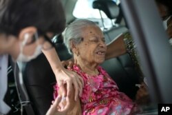 Maria de Lourdes, 101, grimaces as she receives a dose of China's Sinovac Biotech COVID-19 vaccine at a drive-thru vaccination site in the Sambadrome, in Rio de Janeiro, Brazil, Feb. 6, 2021.