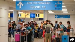 Turistas que llegan a Roma desde cuatro países mediterráneos hacen fila con sus maletas en el aeropuerto Leonardo da Vinci de Roma para ser examinados inmediatamente por COVID-19, el domingo 16 de agosto de 2020.