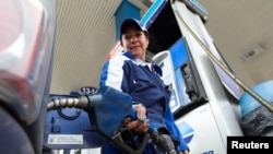 FILE - A woman fills a car with fuel at a gas station in Quito, Ecuador, June 1, 2016. 