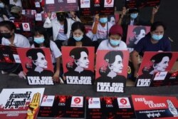 FILE - Protesters hold signs of detained Myanmar civilian leader Aung San Suu Kyi during a demonstration against the military coup in Yangon on Feb. 26, 2021.
