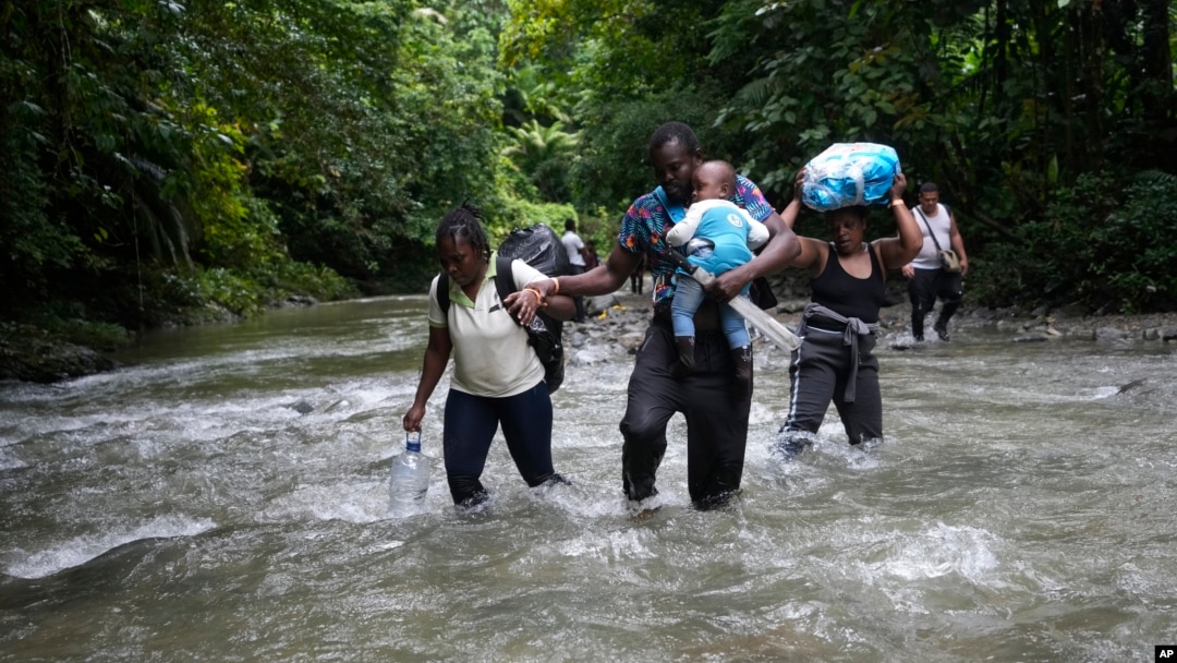 FILE - Haitian migrants wade through a river as they cross the Darien Gap, from Colombia into Panama, hoping to reach the U.S., Oct. 15, 2022. 