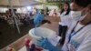 FILE - A woman demonstrates how to clean a toilet bowl at a poor community in Manila, Philippines, on World Toilet Day, an event aimed at improving access to basic sanitation, Nov. 19, 2014.