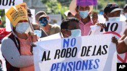 A man holds a sign with a message that reads in Spanish; "Don't steal our pensions," during a protest against the country adopting Bitcoin as legal tender, along the Pan-American Highway, in San Vicente, El Salvador, September 7, 2021. 