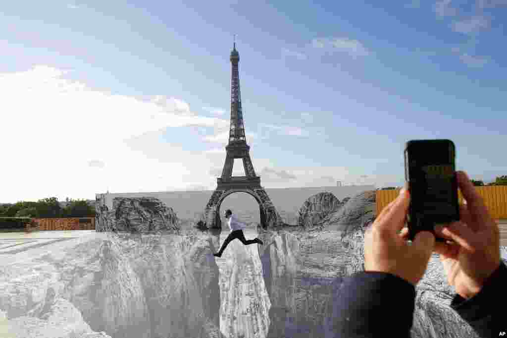 A man jumps on the Trocadero square in front of the Eiffel Tower, where the French artist and photographer known as JR set his artwork, in Paris. 