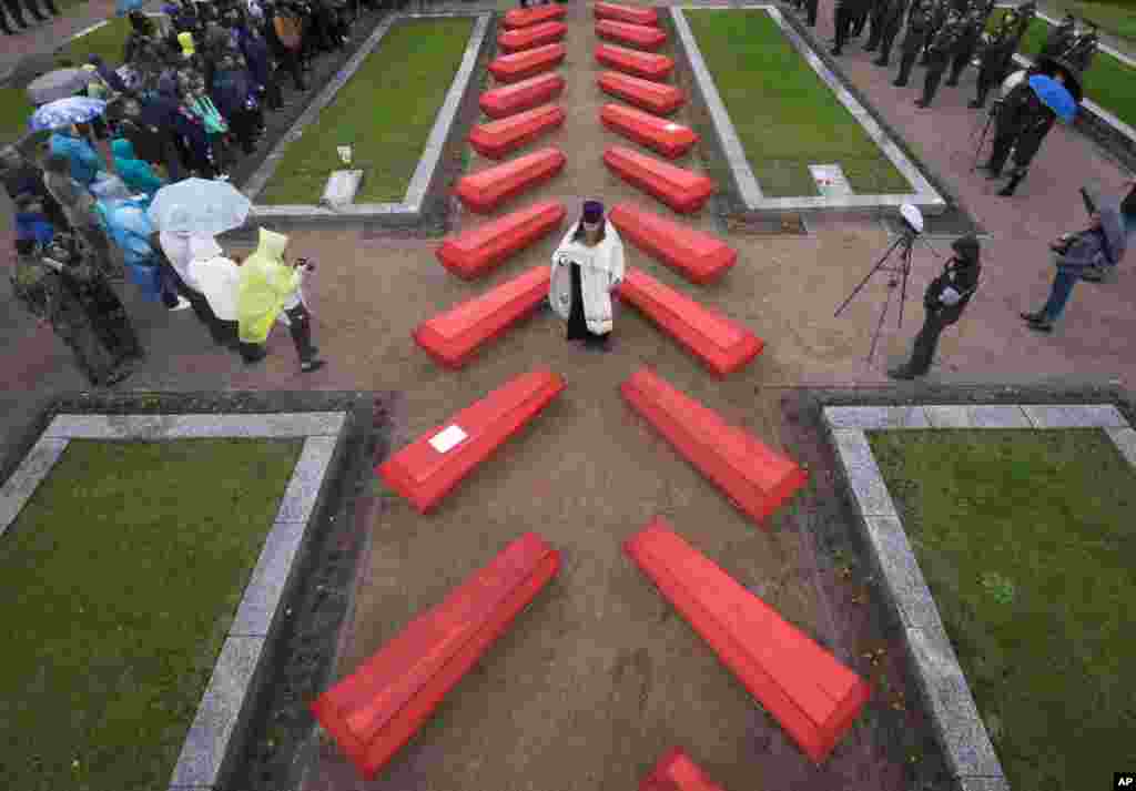 An Orthodox priest conducts a burial ceremony of 228 Soviet soldiers killed during World War II, in a memorial cemetery at Nevsky Pyatachok near Kirovsk, Russia.