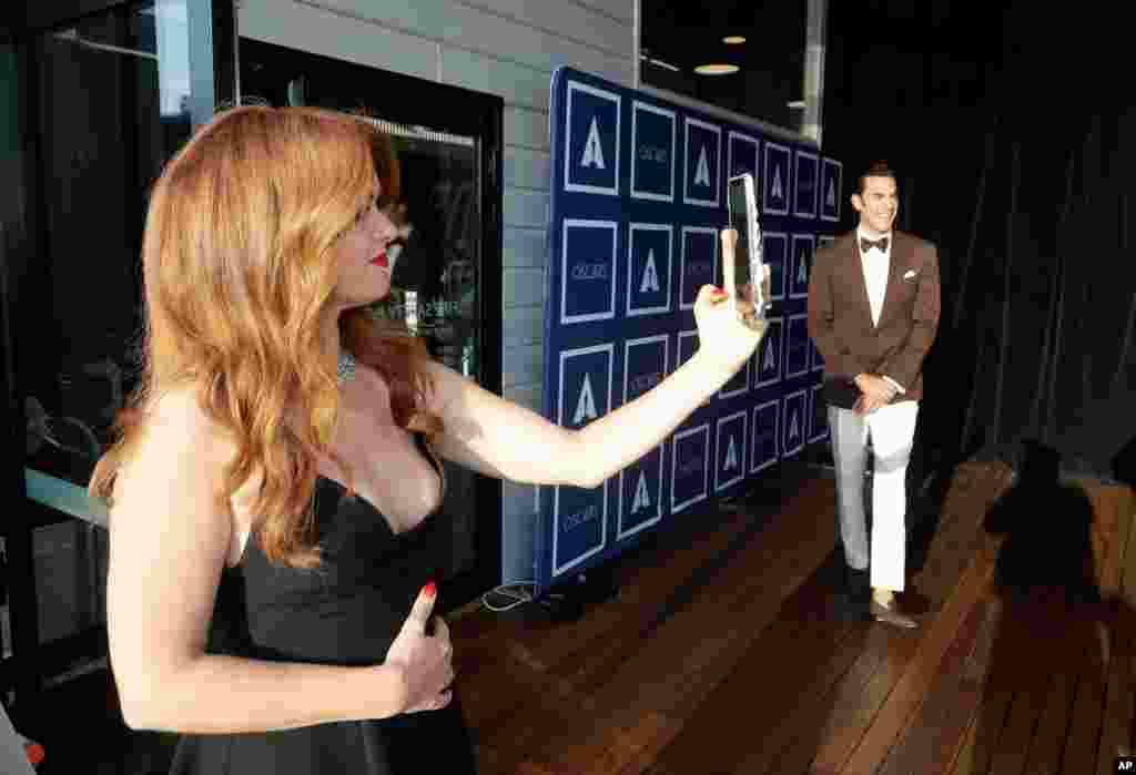 Isla Fisher takes a selfie as Sacha Baron Cohen poses for a photo as they arrive to attend a screening of the Oscars on Monday April 26, 2021 in Sydney, Australia. (AP Photo/Rick Rycroft, Pool)