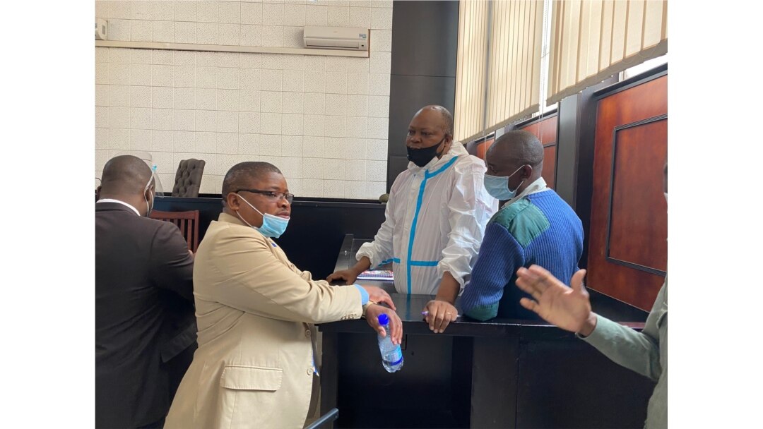 Opposition leader Job Sikhala, wearing personal protective equipment, talks to Harrison Nkomo of Zimbabwe Lawyers for Human Rights, in the courthouse at Harare Magistrate’s Court, Jan. 14, 2021. (Columbus Mavhunga/VOA)