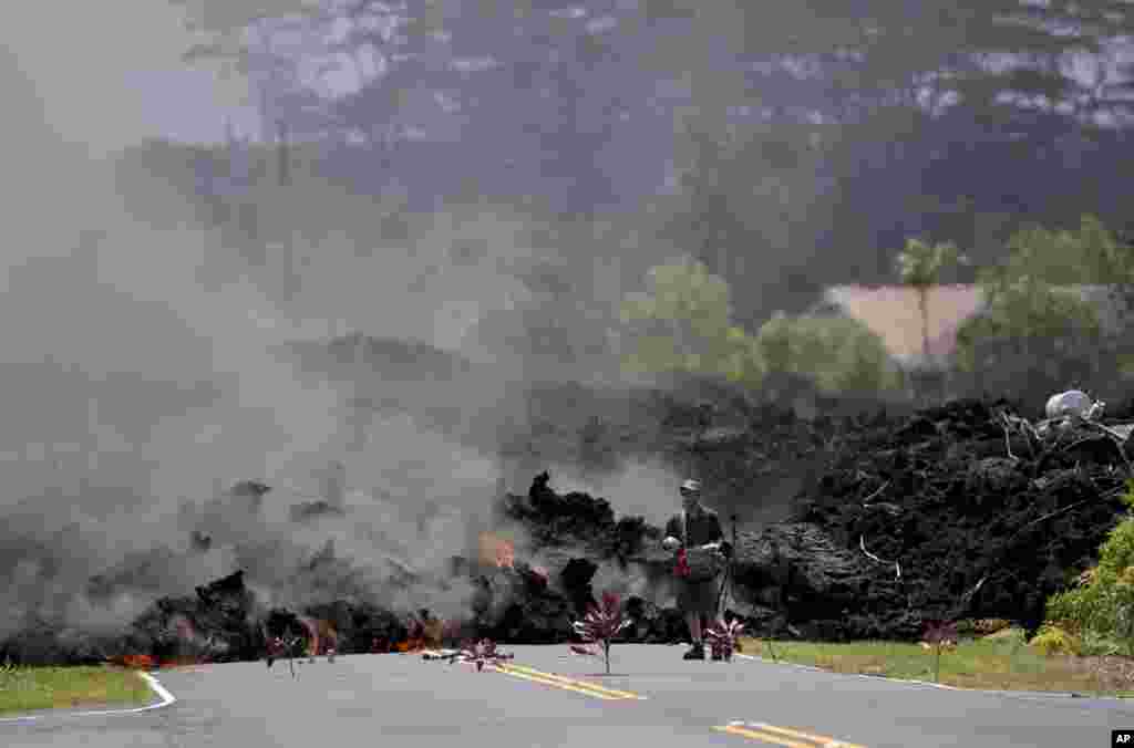 A man films the lava in the Leilani Estates neighborhood, Saturday, May 5, 2018, in Pahoa, Hawaii. Hundreds of people on the Big Island of Hawaii are preparing for what could be weeks or months of upheaval as the dangers from the erupting Kilauea volcano grow. (AP Photo/Marco Garcia)