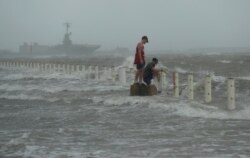 Two men stand near a seawall as Hurricane Hanna makes landfall, July 25, 2020, in Corpus Christi, Texas.