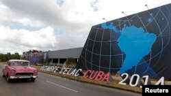 Un auto pasa frente al sitio donde se desarrolla la cumbre de la CELAC, en La Habana.