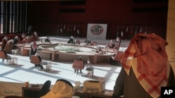 FILE - Saudi journalists watch a screen showing the meeting of the 41st Gulf Cooperation Council taking place in Al Ula, Saudi Arabia, Jan. 5, 2021.