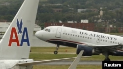 Un avión de US Airways despega detras de otro de American, en el Aeropuerto Nacional Ronald Reagan de Washington.