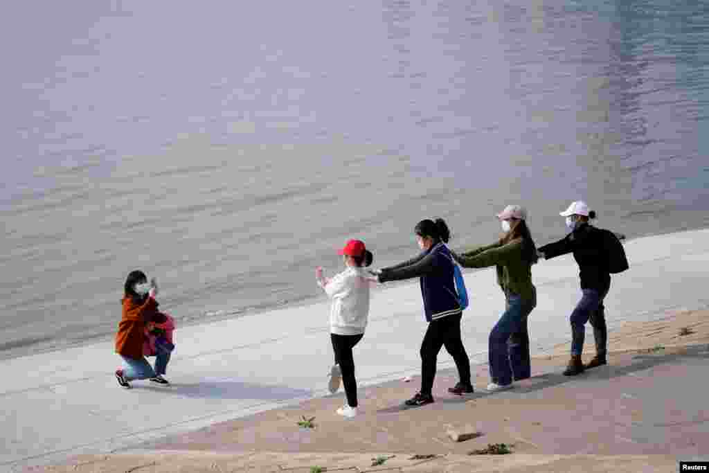 Las personas con máscaras faciales posan junto al río Yangtze en Wuhan, provincia de Hubei, el 4 de abril de 2020.