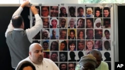 Relatives of the deceased and people directly affected by the Grenfell Tower fire, sit in front of a photo montage of the those who died, as they react to the final report into the fire being released in London, Sept. 4, 2024. 