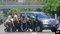 Polisi berlindung di balik kendaraan saat terjadi baku tembak dekat lokasi ledakan di Jakarta (14/1). 