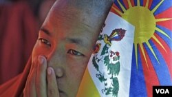 Seorang biarawan Budha memegang bendera Tibet. Aksi bakar diri sebagai bentuk protes terhadap pemerintahan Tiongkok akhir-akhir ini meningkat.