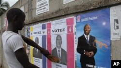 An unidentified man reacts to a campaign poster for incumbent President Laurent Gbagbo, as presidential campaigning kicked off 15 Oct 2010 in Abidjan