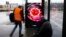 Two men wait at a bus stop with a screen displaying a symbol photo of the novel coronavirus in Berlin, Germany, March 12, 2020.