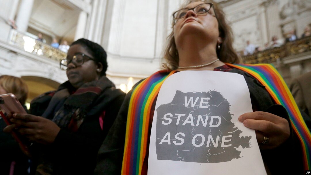 Pastor Annie Steinberg-Behrman (kanan) dari Gereja Metropolitan Community, memegang kertas pernyataan dukungan saat menghadiri rapat di Balai Kota San Francisco untuk menekankan lagi komitmen kota itu sebagai kota perlindungan, November 2016. (AP/Jeff Chiu)