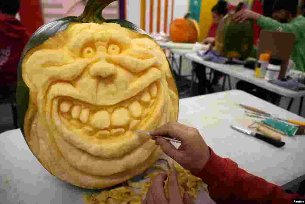 An artist works on a pumpkin carving of film character Slimer the ghost in the workshop of creative group Sand In Your Eye ahead of the annual pumpkin trail in Hebden Bridge, Britain.