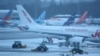 Sejumlah staf bandara membersihkan landasan pacu di Bandara Manchester, Inggris, dengan menggunakan traktor pada 5 Januari 2025. (Foto: Reuters/Phil Noble)