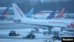 Sejumlah staf bandara membersihkan landasan pacu di Bandara Manchester, Inggris, dengan menggunakan traktor pada 5 Januari 2025. (Foto: Reuters/Phil Noble)