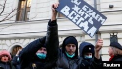 FILE - Police officers restrain a supporter of the human rights group International Memorial outside a court building during a hearing of the Russian Supreme Court to consider the closure of International Memorial in Moscow, Dec. 28, 2021. 