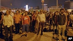 Erdem Gunduz, left, and dozens of people stand silently on Taksim Square in Istanbul early Tuesday, June 18, 2013.