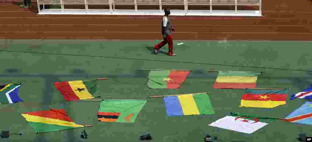 Un homme passe devant les drapeaux nationaux des équipes participantes avant la cérémonie d&#39;ouverture le premier match de footballdu Groupe A de la Coupe d&#39;Afrique des Nations à Bata, en Guinée équatoriale, le vendredi 16 janvier 2015.